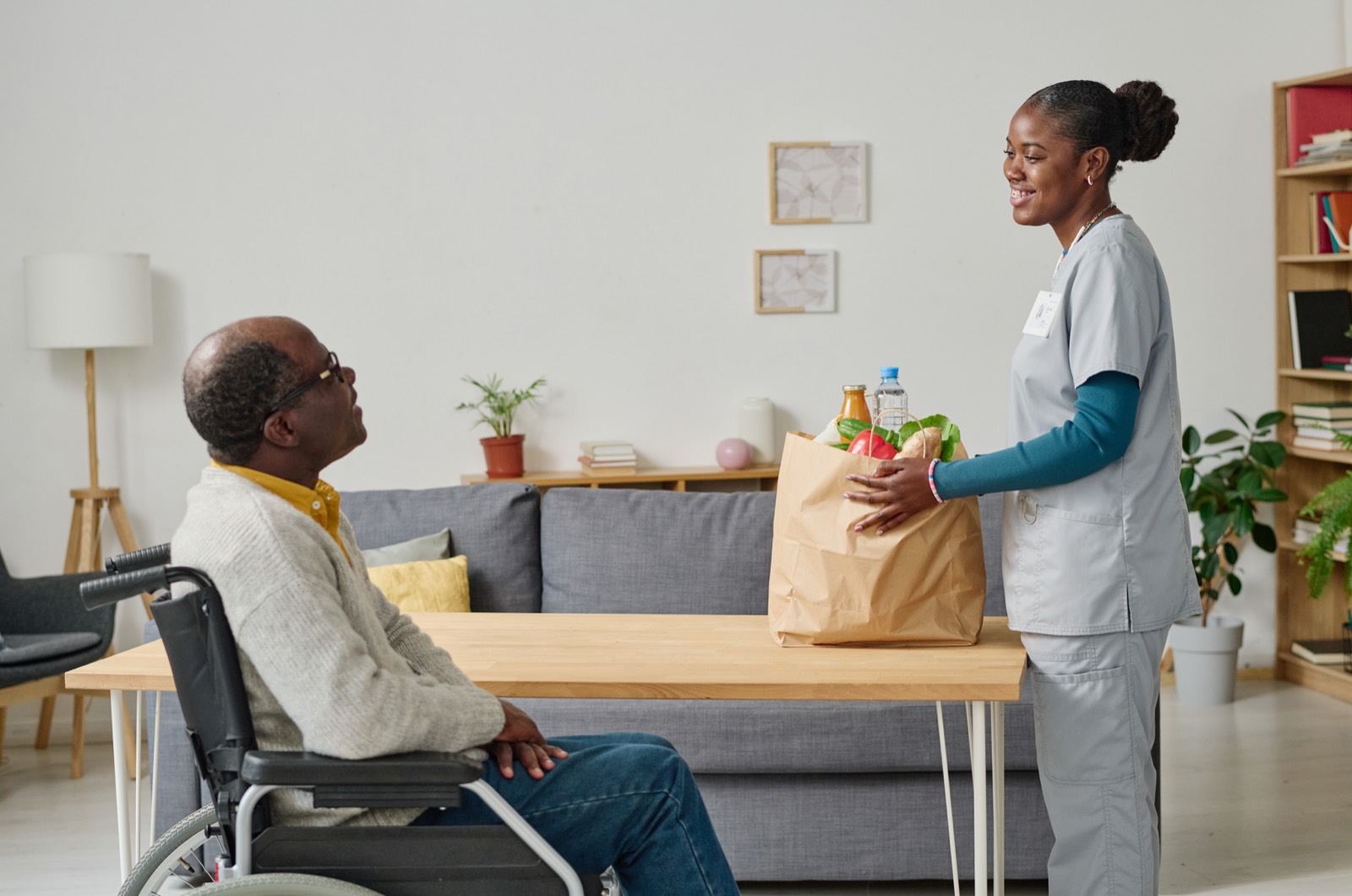 A Helen's Home Care caregiver bringing groceries to a senior man at home